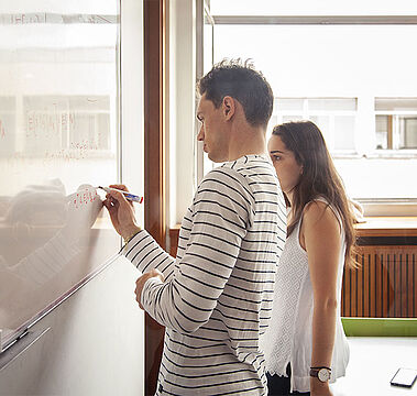 Deux étudiants en train de résoudre un problème au tableau